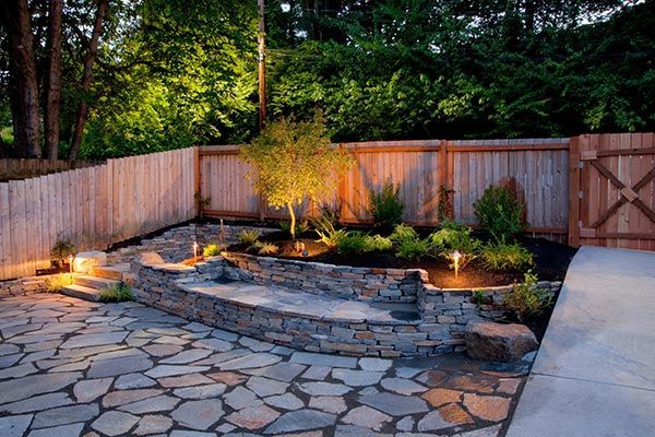 A backyard with a stone patio and a wooden fence.