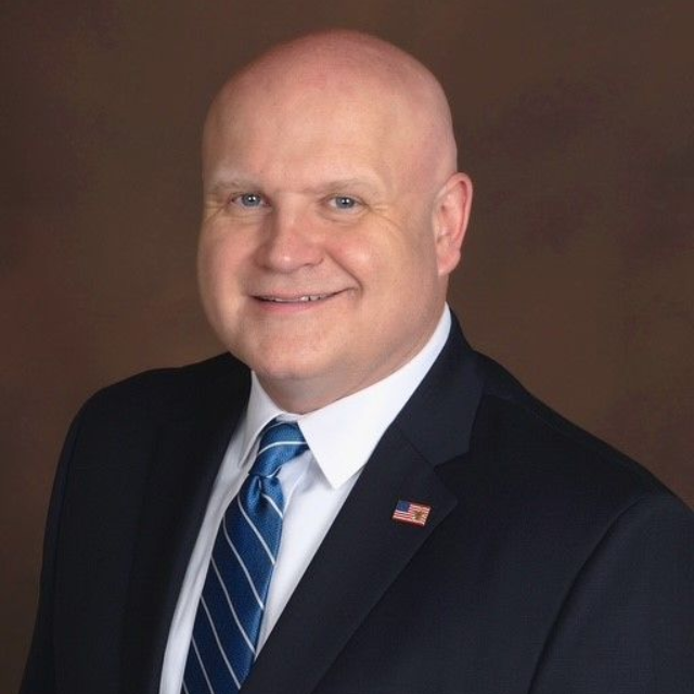 A woman wearing hoop earrings and a white shirt is smiling for the camera.
