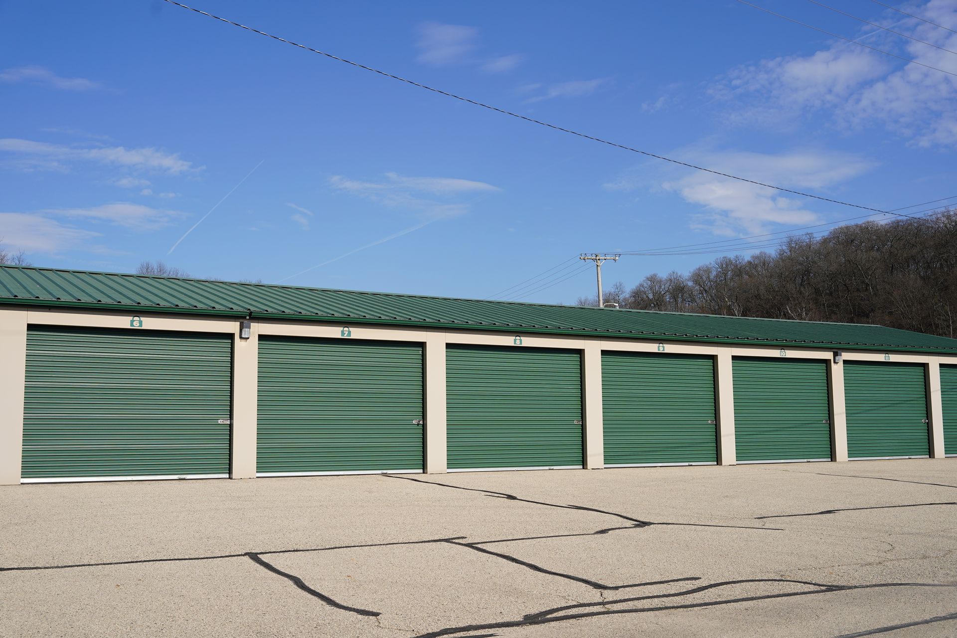 Storage units with green doors and roof under a blue sky. Storage units with green doors and roof under a blue sky.