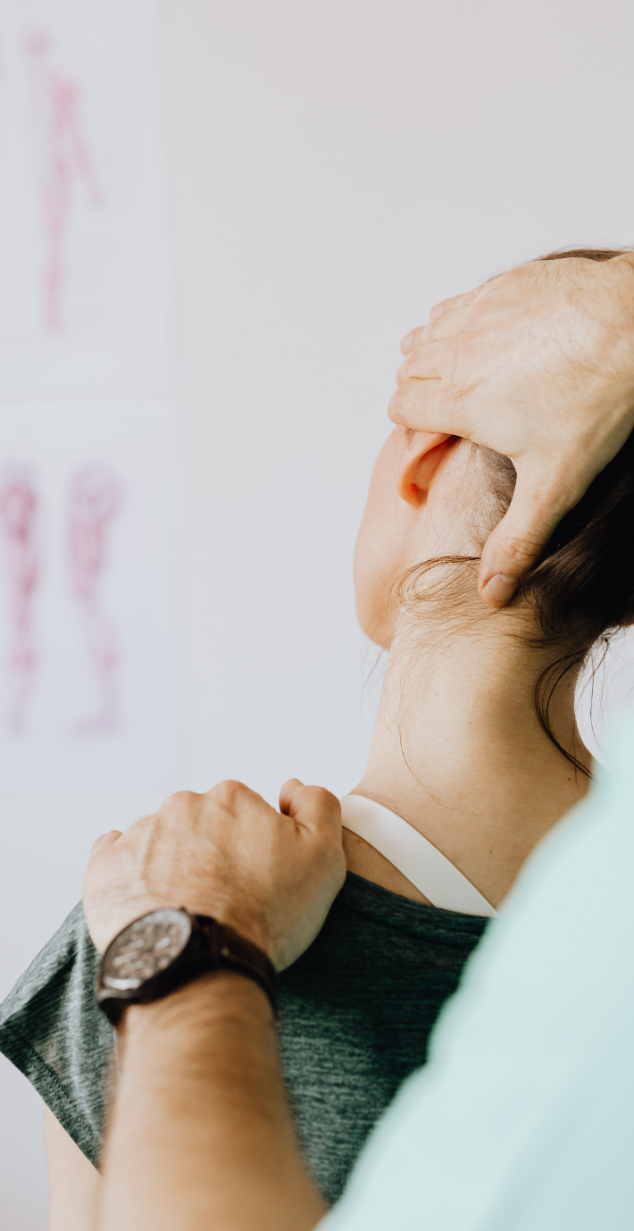 Chiropractor adjusting a patient's neck. The patient's face is visible as they receive treatment.