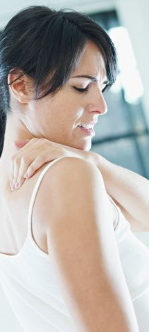Woman touching her shoulder, expressing pain with her face.