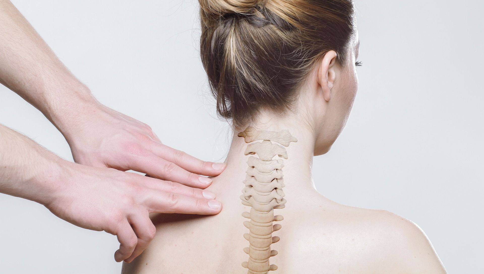 Hands gently touching a woman's neck and shoulders, showing an overlay of the spine.
