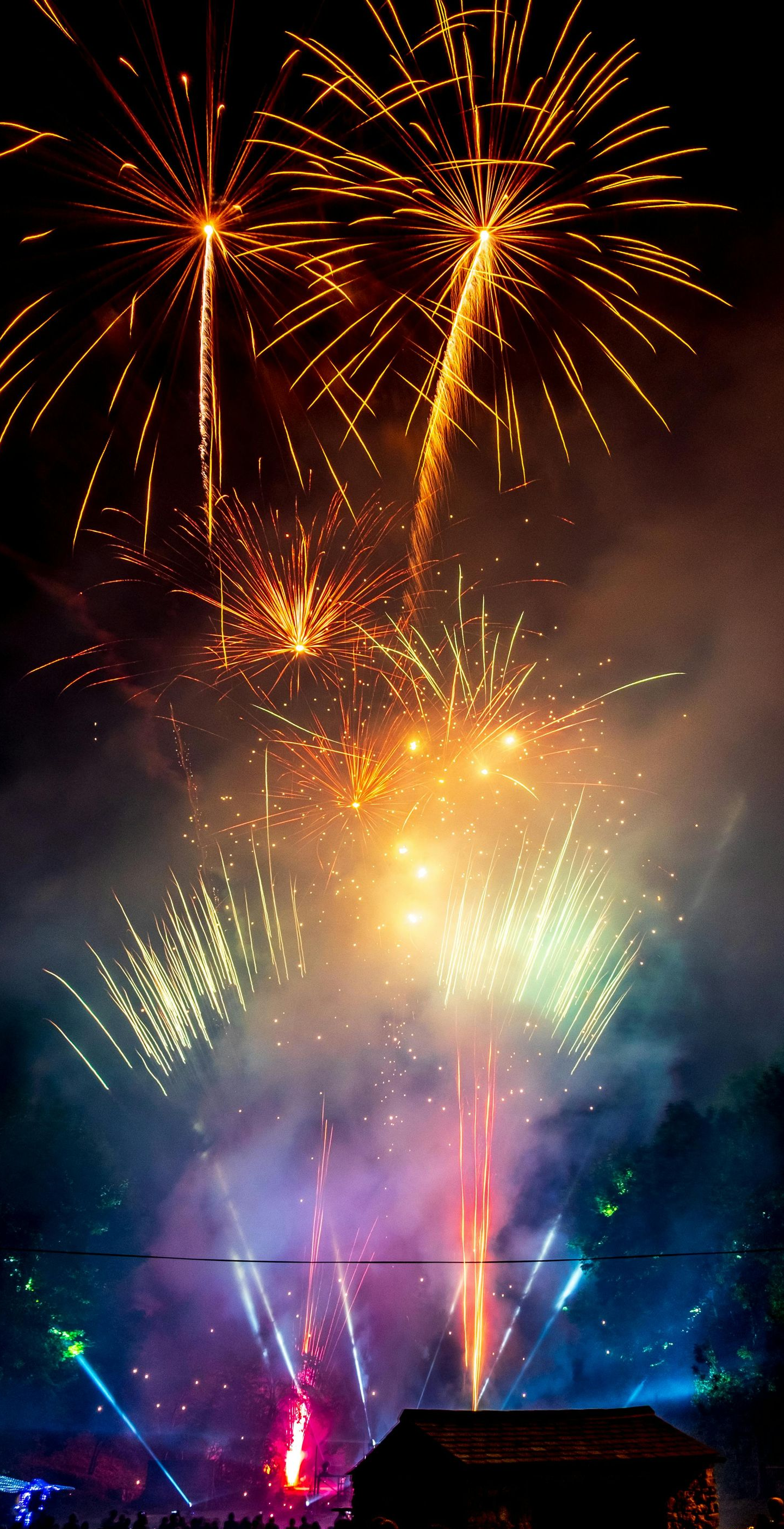 Fireworks display over a crowd, with colorful bursts and smoke against a dark sky.