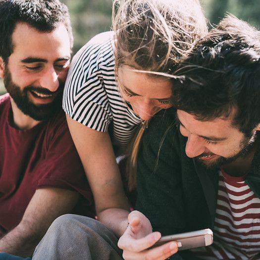 A group of people are looking at a cell phone together.