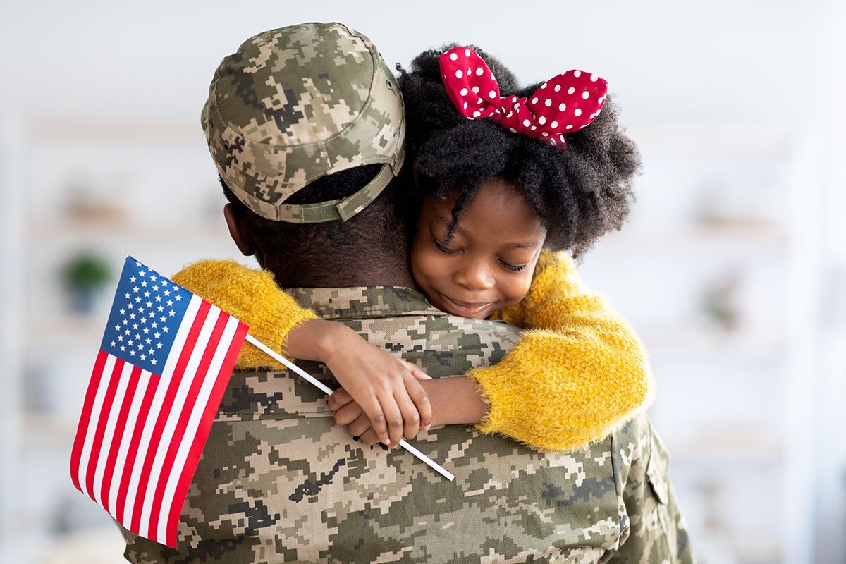 Black veteran and his daughter holding a flag