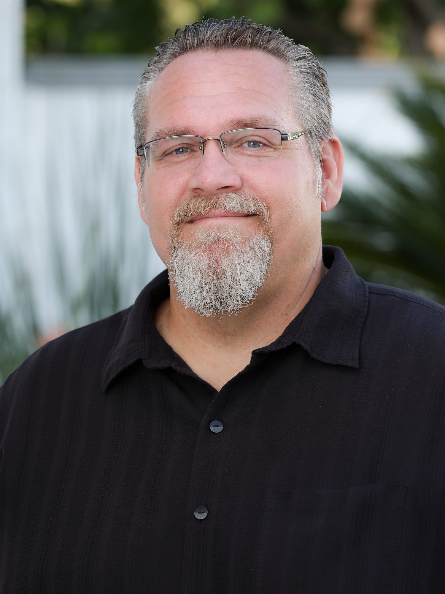 a man with glasses and a beard is wearing a black shirt