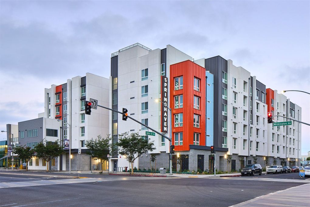 a large apartment building is sitting on the corner of a city street .