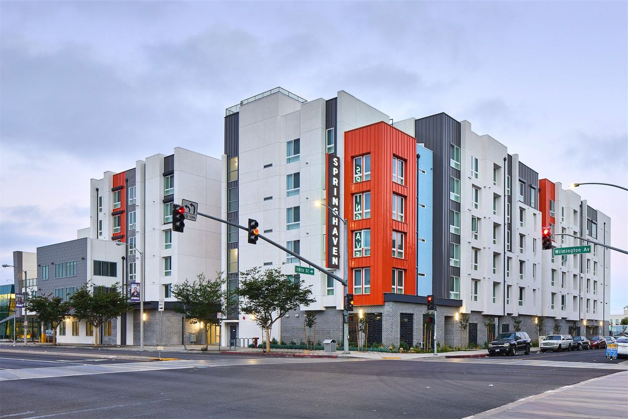 a large apartment building is sitting on the corner of a city street .