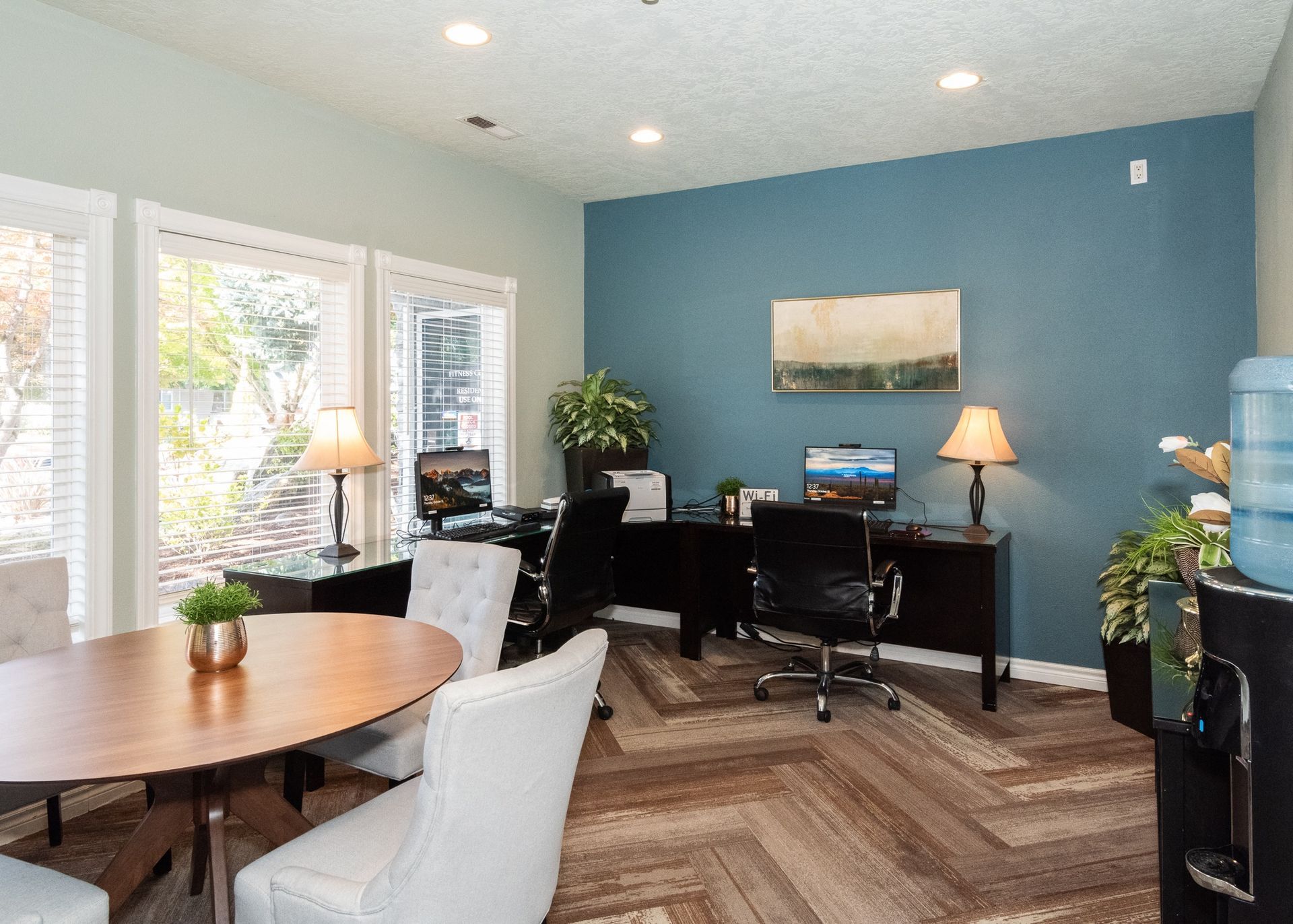 Interior leasing office with desks, computers, and seating along a blue accent wall.