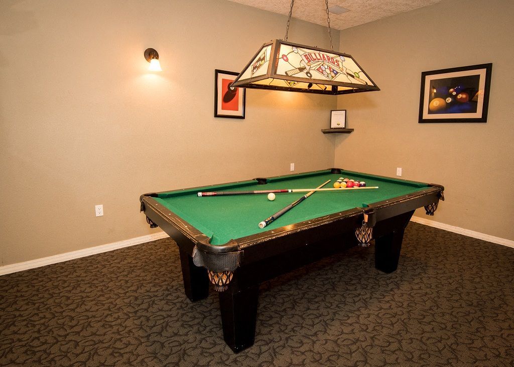 Indoor game room with a pool table, overhead lamp, and wall art.