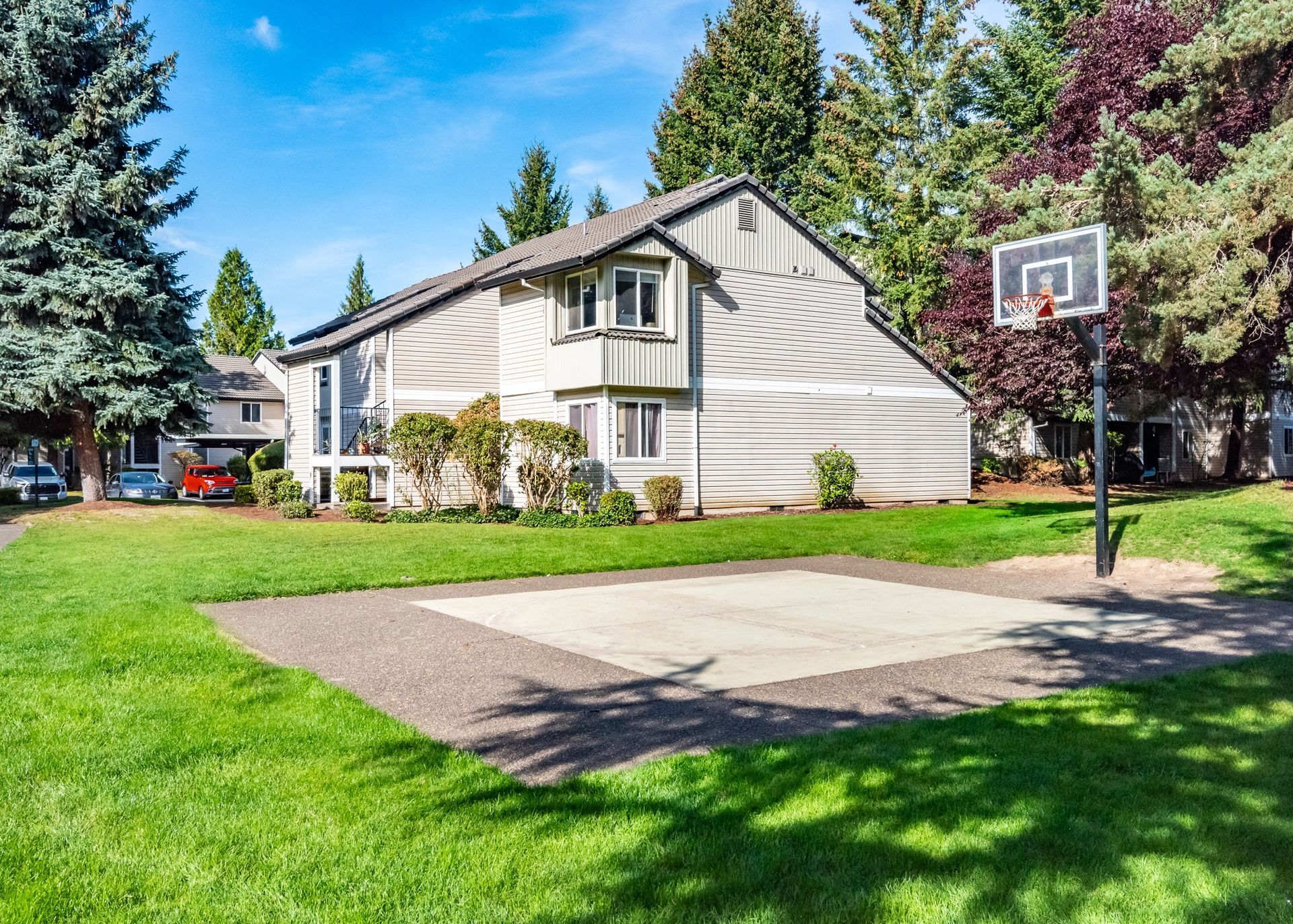 Exterior view of a multi-family building with a basketball hoop and green lawn.
