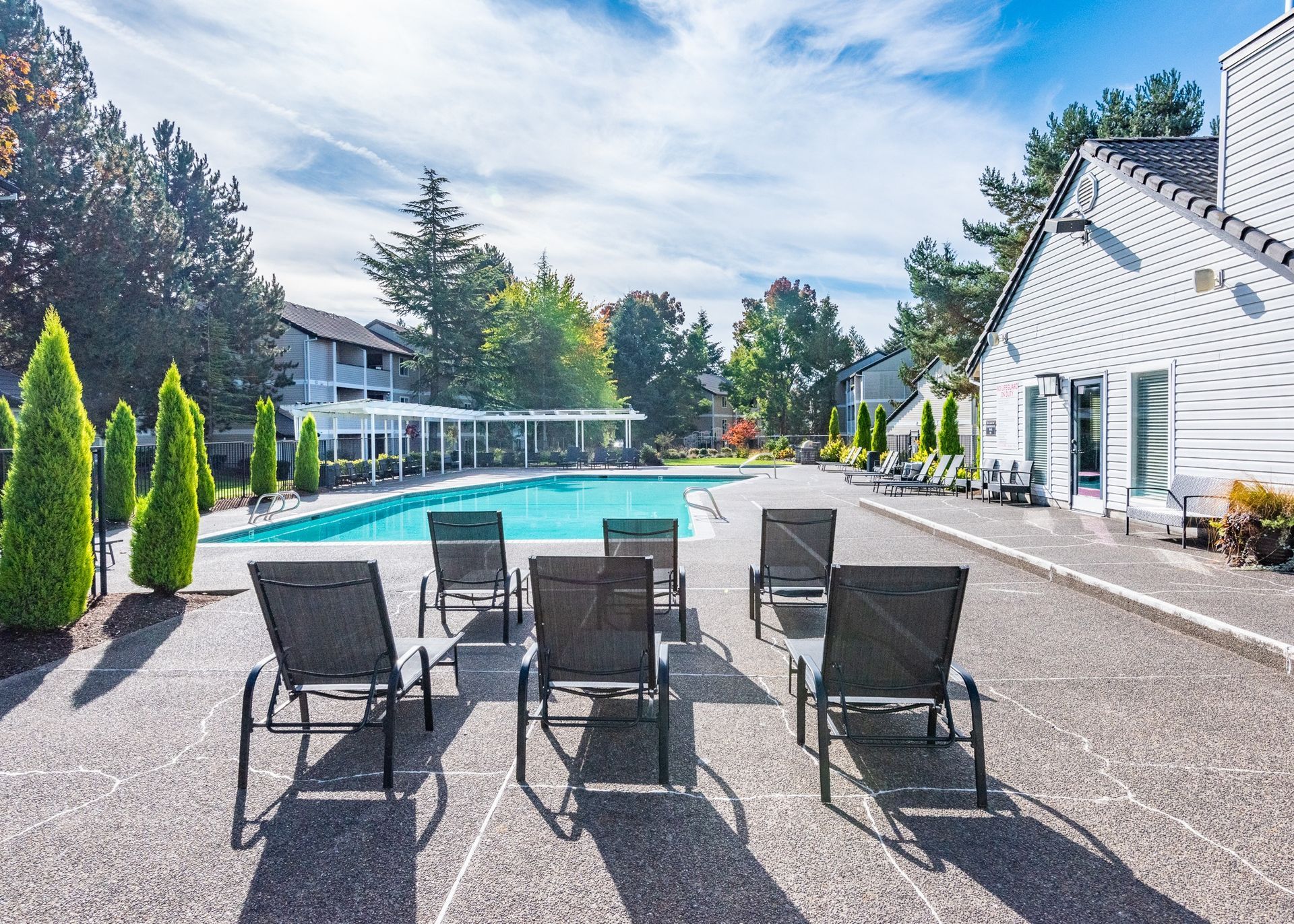 Outdoor pool area with lounge chairs and surrounding buildings in the background.