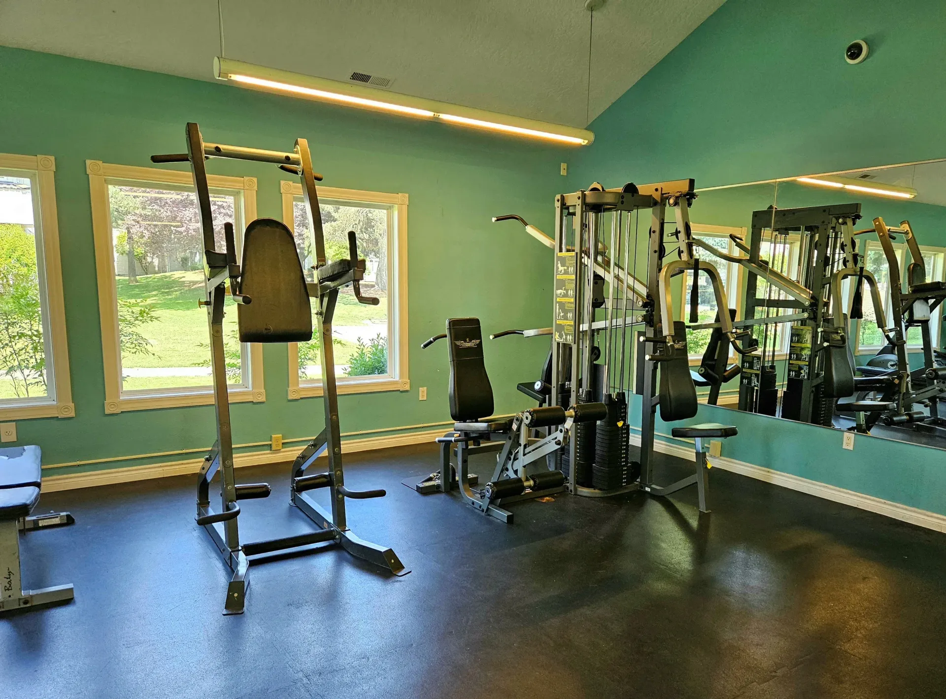 Gym area with weight machines, a bench, and a mirrored wall.