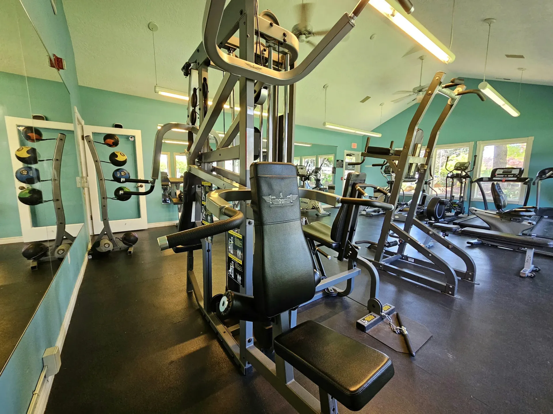 Fitness center in apartment community with weight machines, cardio machines, and wall mirrors.