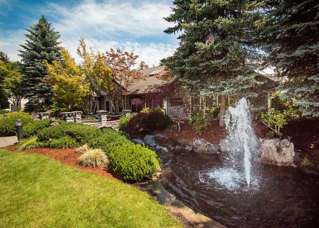 Exterior community courtyard with a fountain, pond, and landscaped greenery.