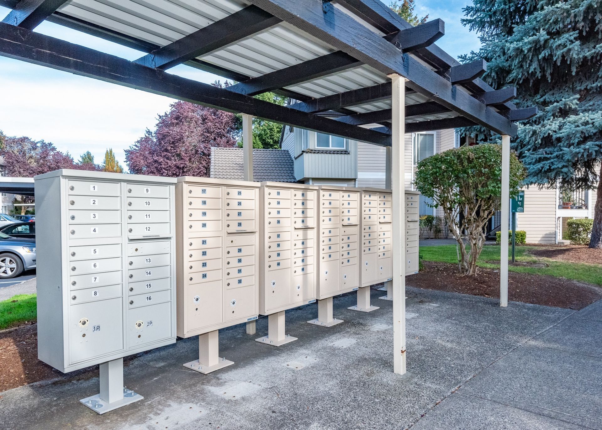 Row of apartment mailboxes under a metal canopy in a residential complex.