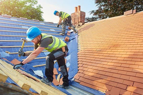 Two men are working on the roof of a house.