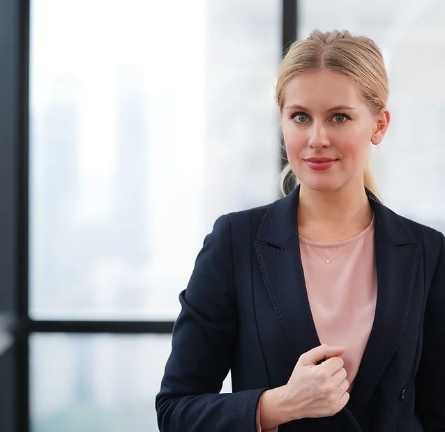 A woman in a business suit is standing in front of a window