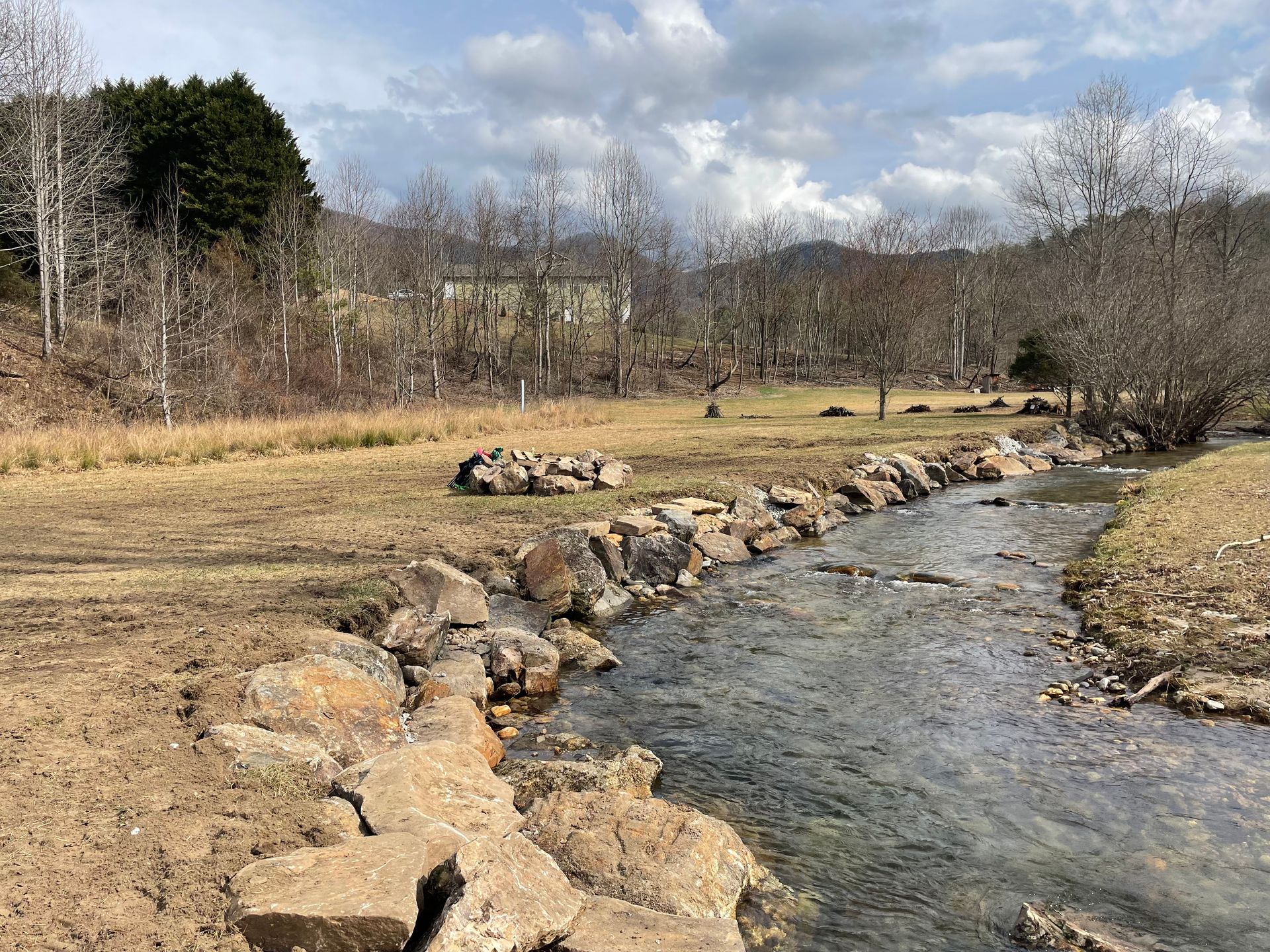 A small stream running through a field surrounded by rocks.