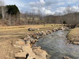 A small stream running through a field surrounded by rocks.