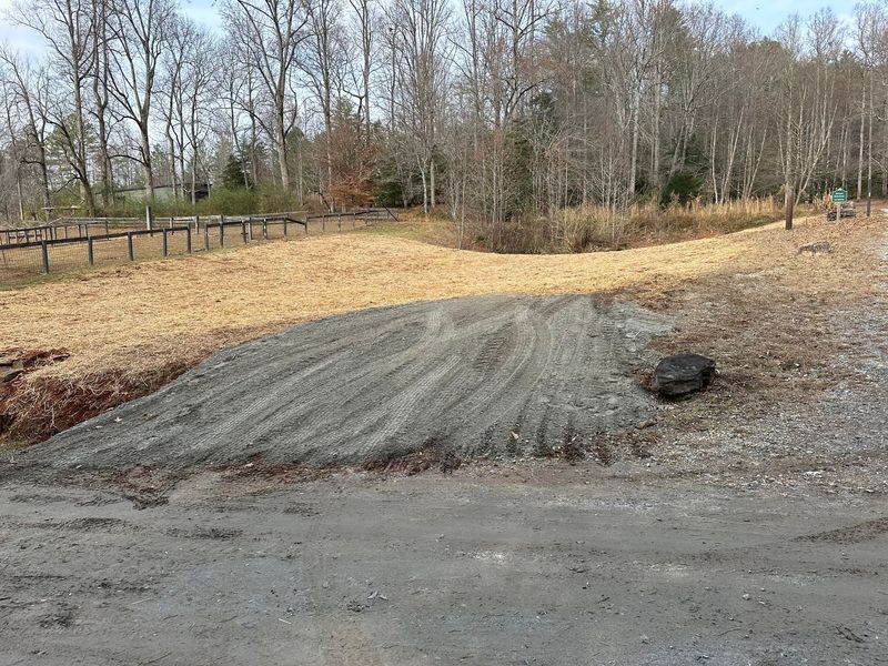 A dirt road leading to a picnic area with trees in the background.