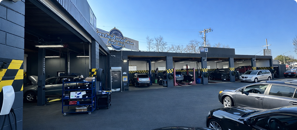 Auto shop parking lot with several cars under covered bays and a silver car in front | Costa Auto Care and TIre