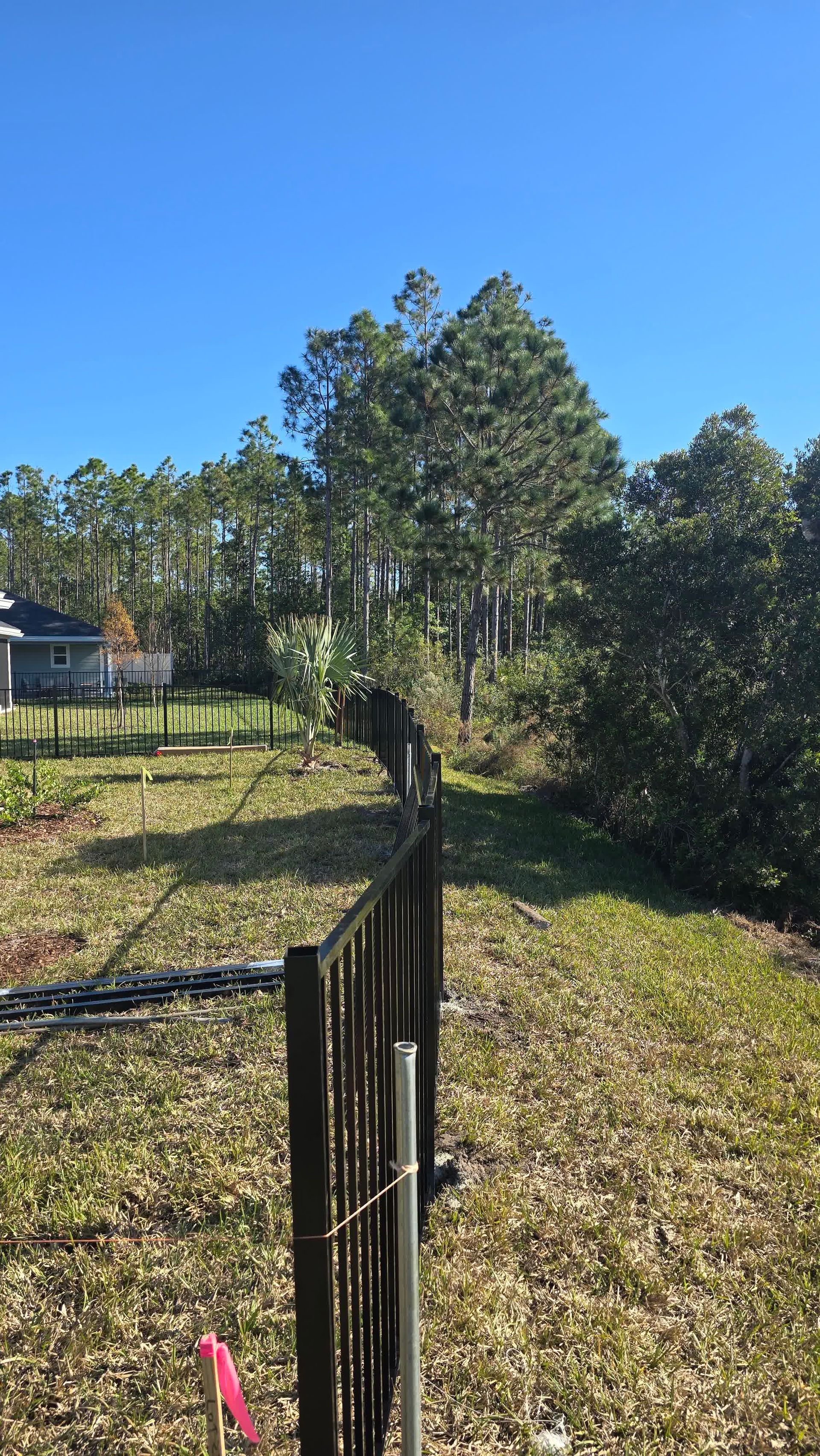 Person using a power tool to sand and polish an aging wooden fence, giving it a renewed appearance.