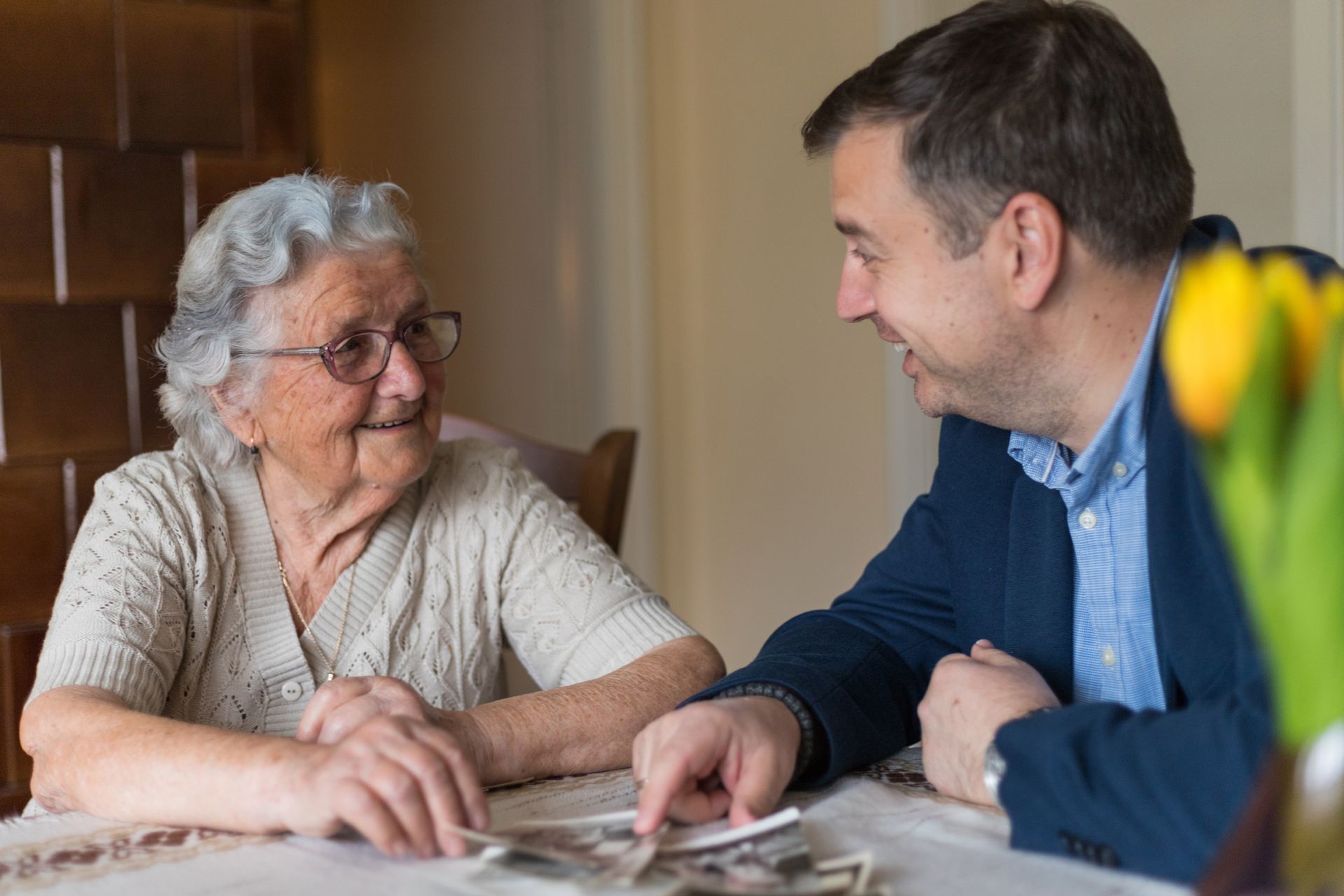 Woman in glasses and man smiling, looking at photos at a table.