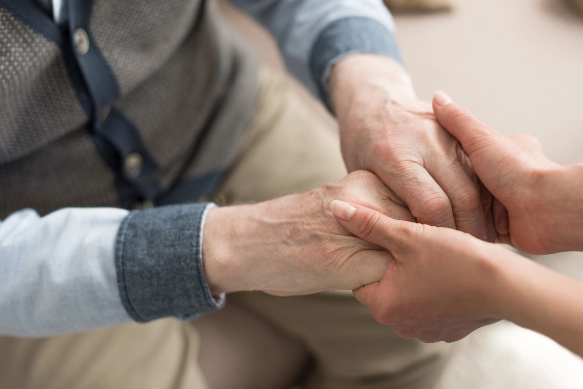A woman is holding the hand of an older man.