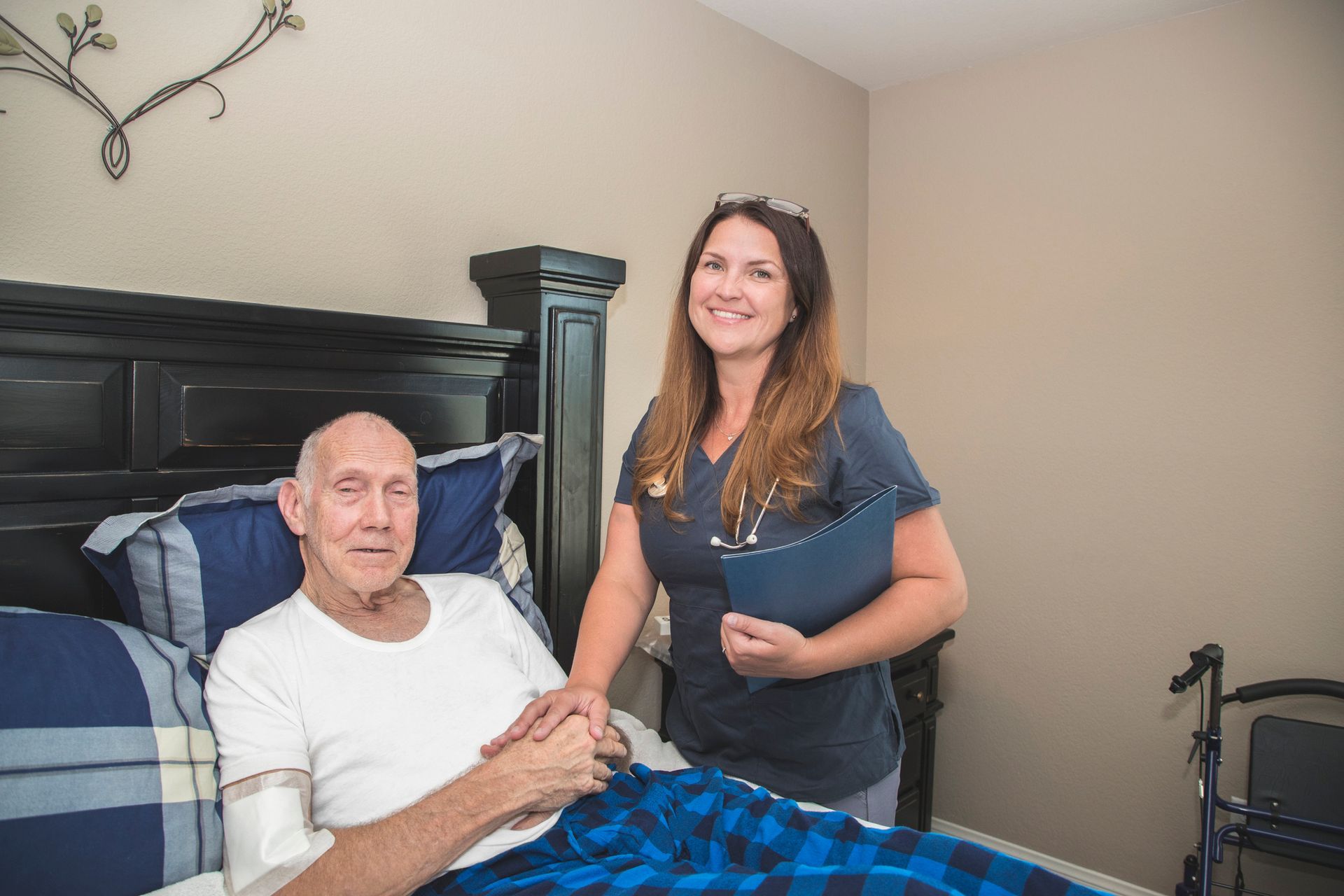 A nurse is standing next to an elderly man in a bed.