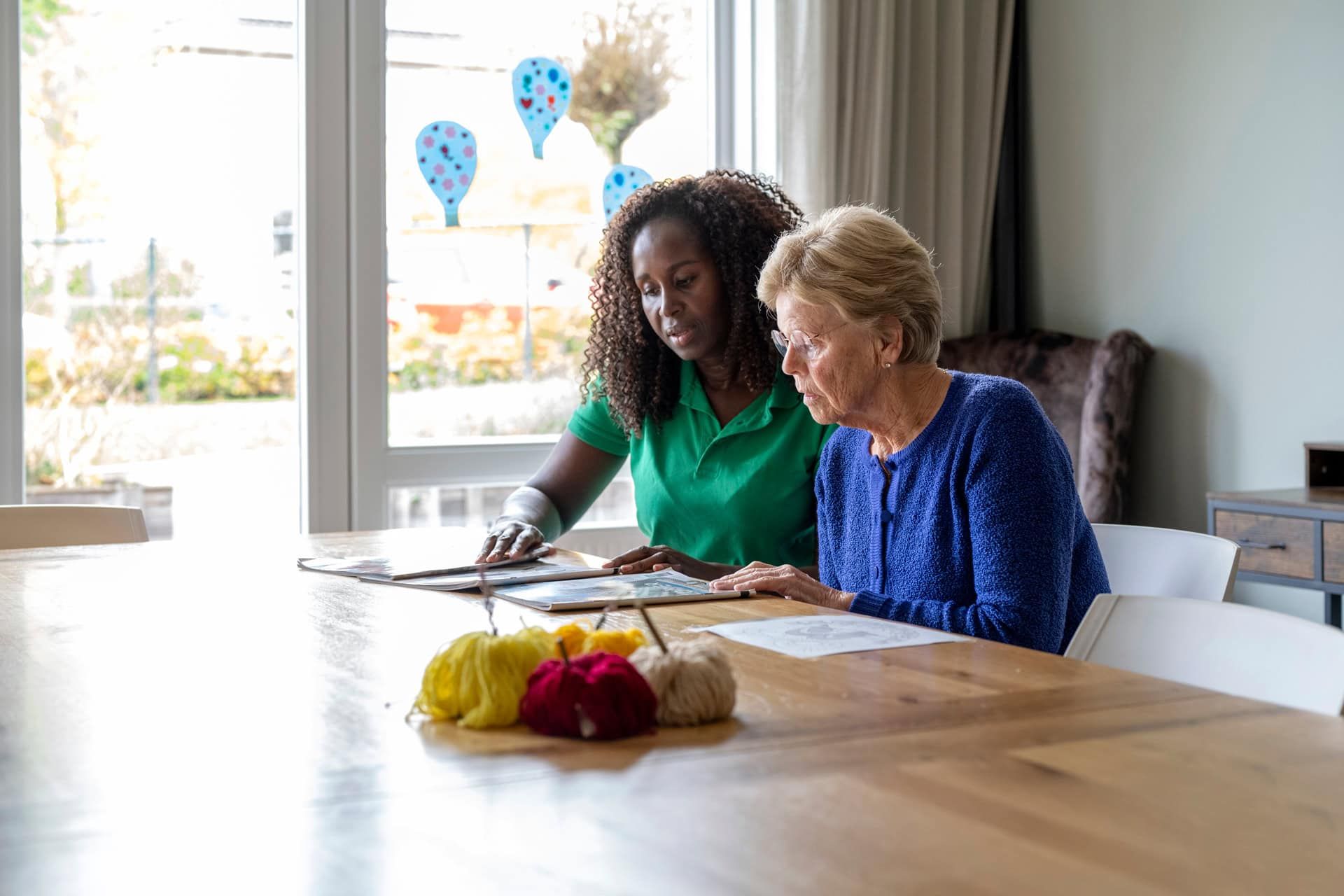 A nurse is sitting at a table with an elderly woman.