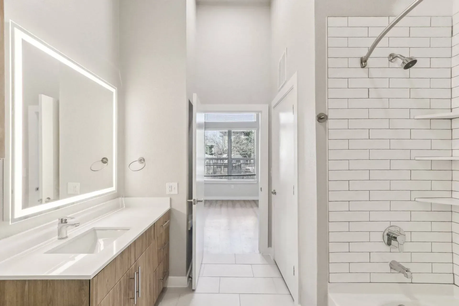 Modern bathroom with long vanity, large mirror, and shower with white subway tiles.