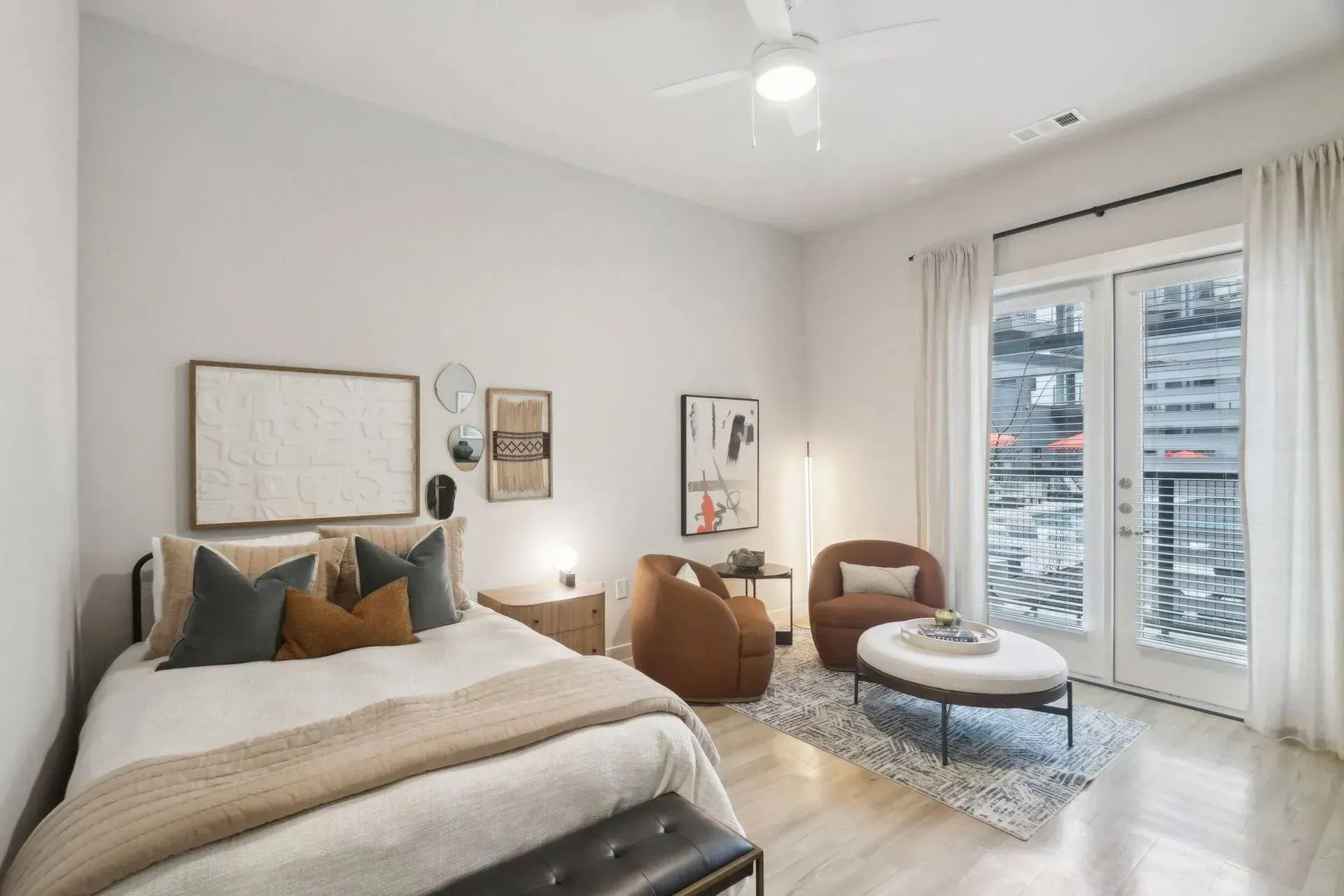 Bedroom with bed, sitting area, balcony, neutral colors, modern decor.