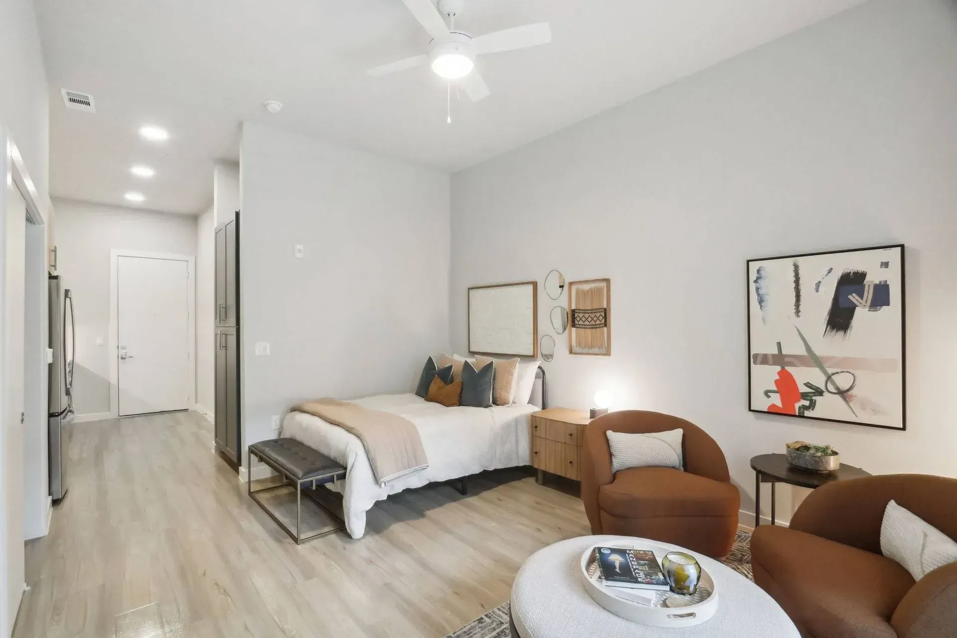 Modern studio apartment interior with bed, seating area, and artwork.