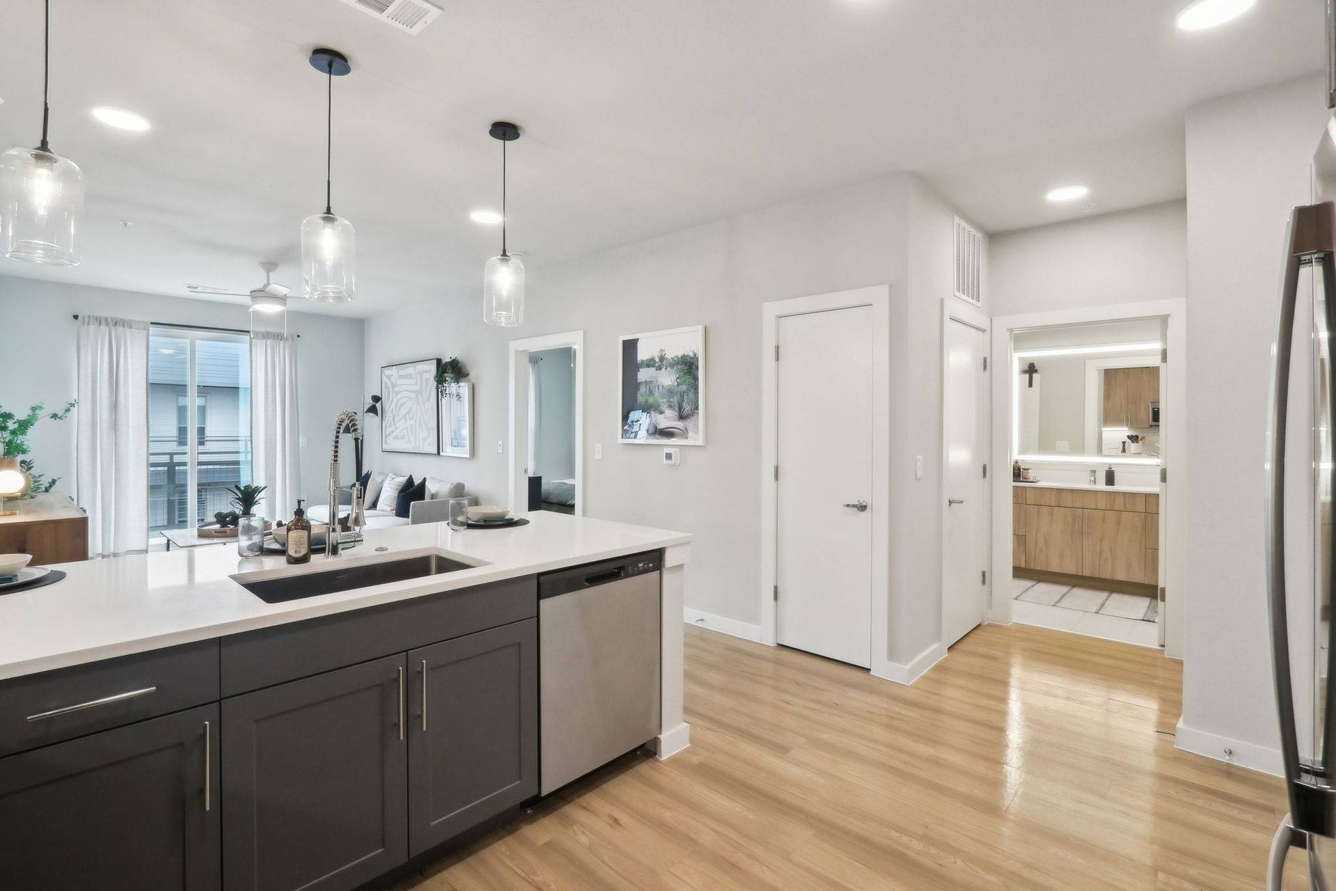 Open-concept modern kitchen with island, pendant lights, and living area.