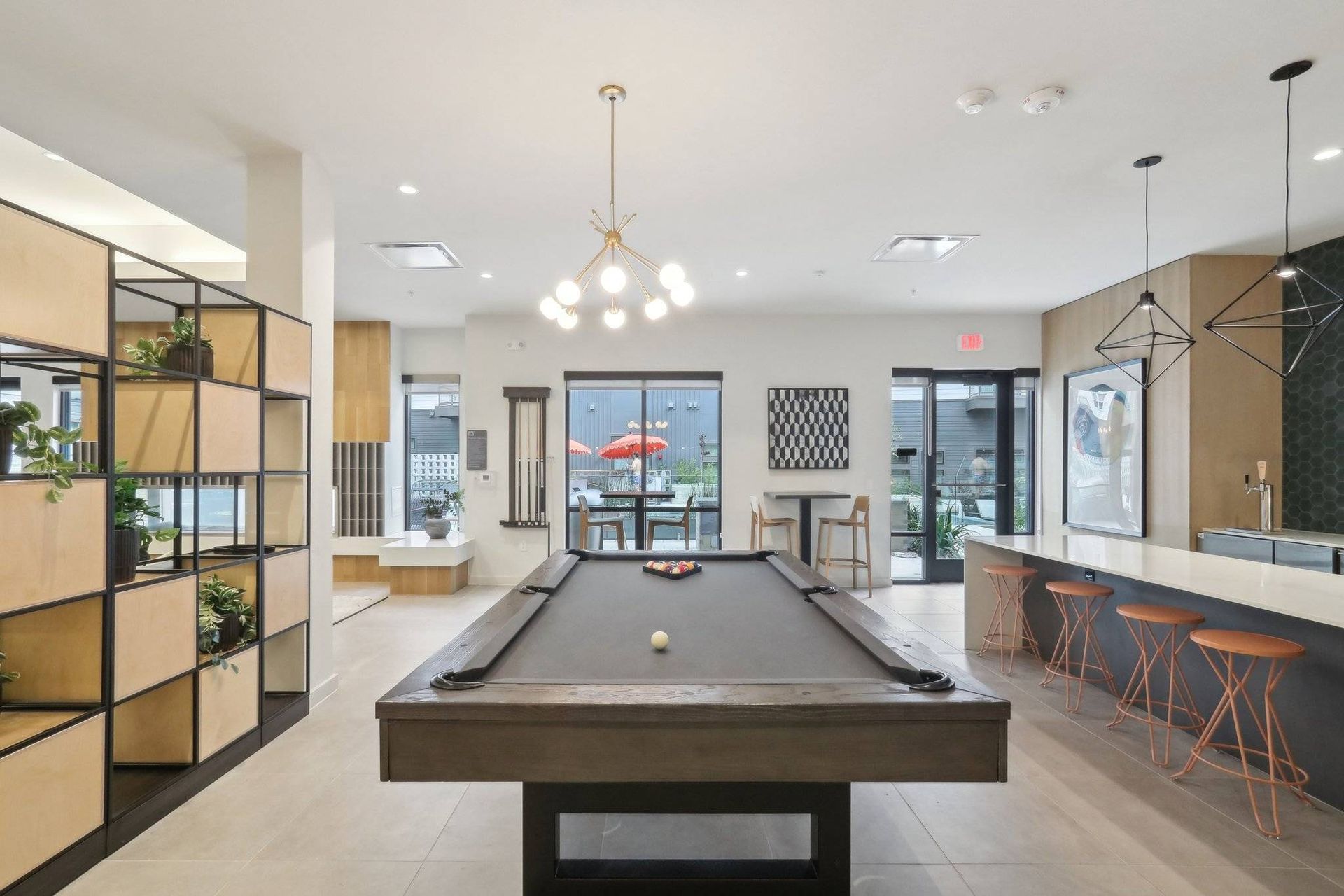 Interior community lounge with a pool table, bar seating, and shelving.