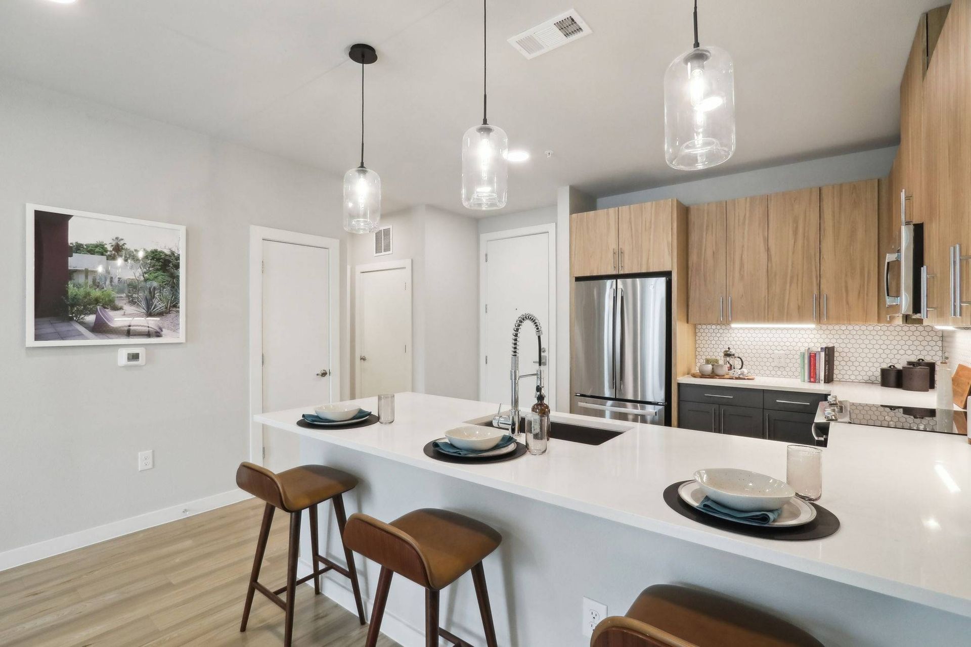 Modern kitchen with island, pendant lights, and stainless steel appliances.