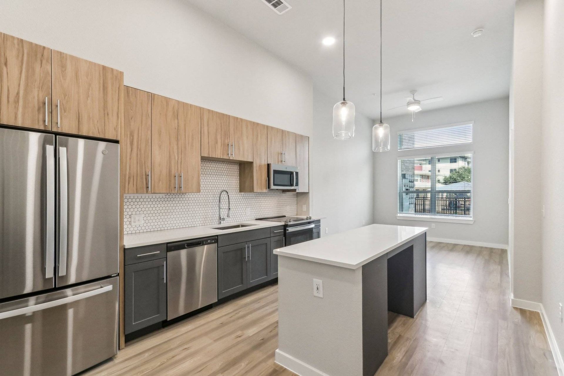 Modern kitchen with wood upper cabinets, gray lower cabinets, stainless steel appliances, and an island.
