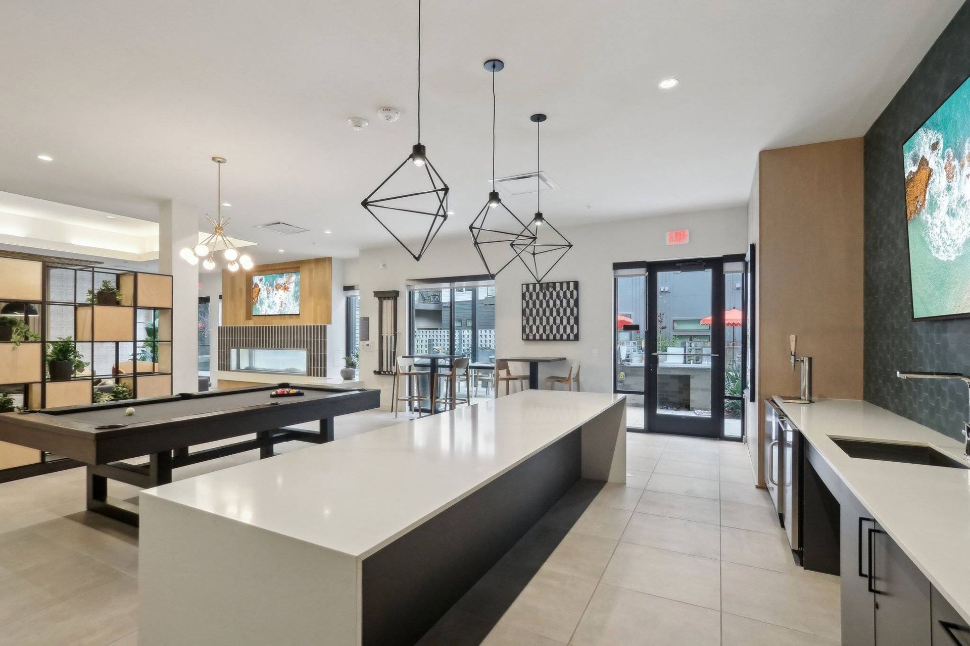 Interior view of a modern community lounge with a pool table, long white island, and seating.