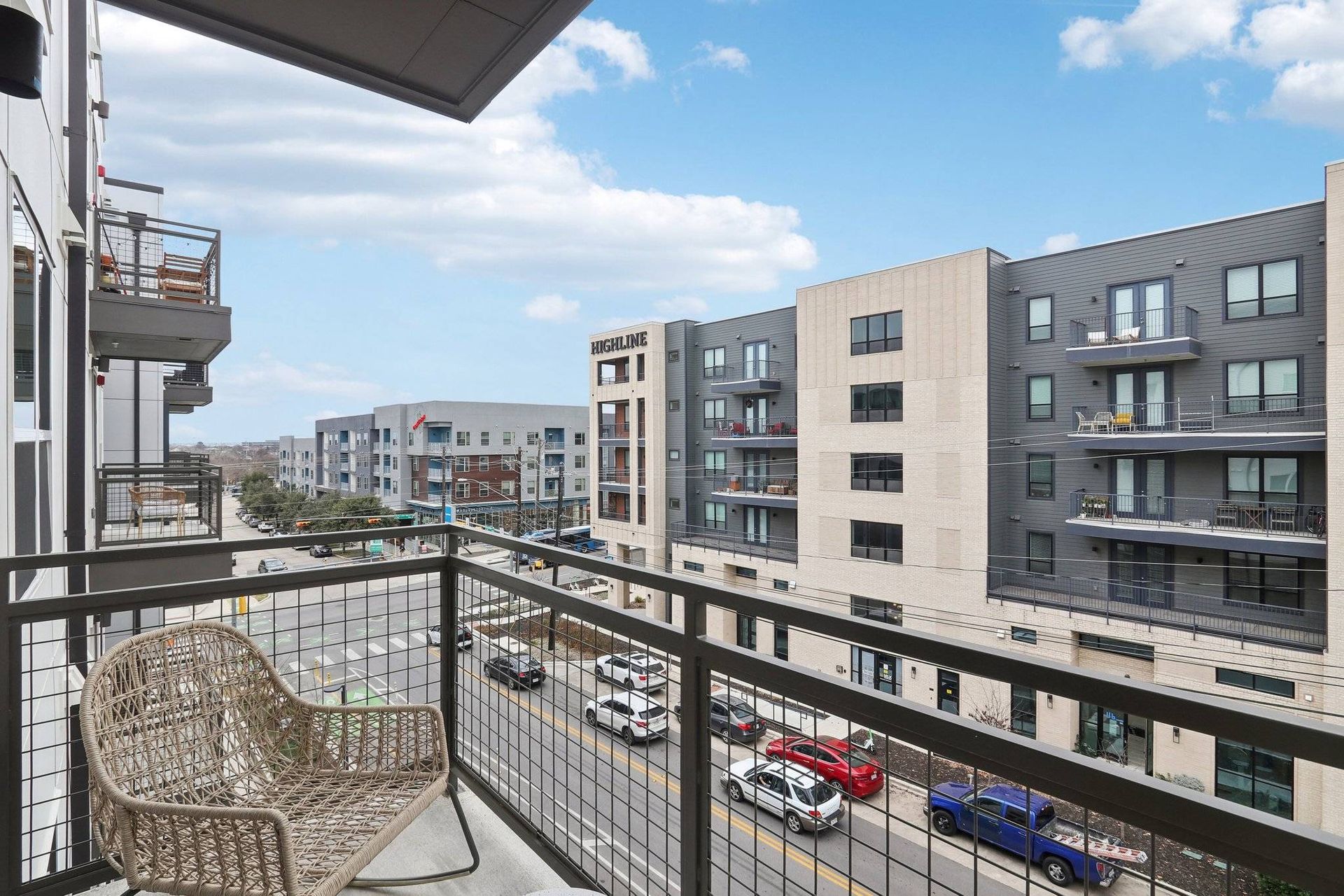 Balcony view overlooking a modern apartment complex with neighboring buildings and a street below.