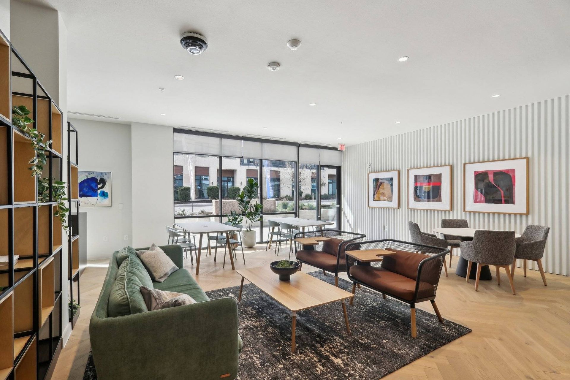 Contemporary resident lounge with a green sofa, seating, and large windows.