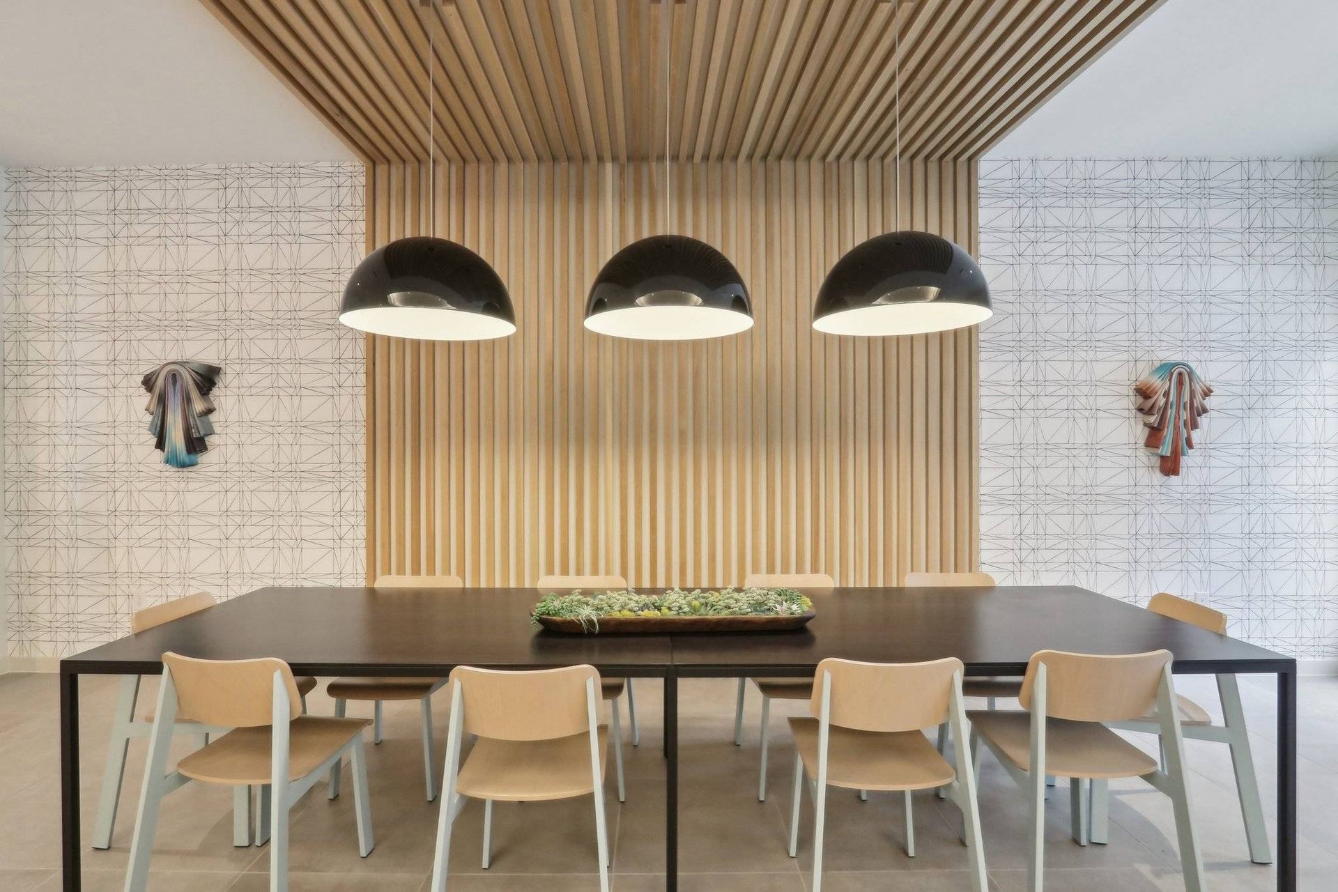 Modern communal dining area with a long table, chairs, and pendant lights.