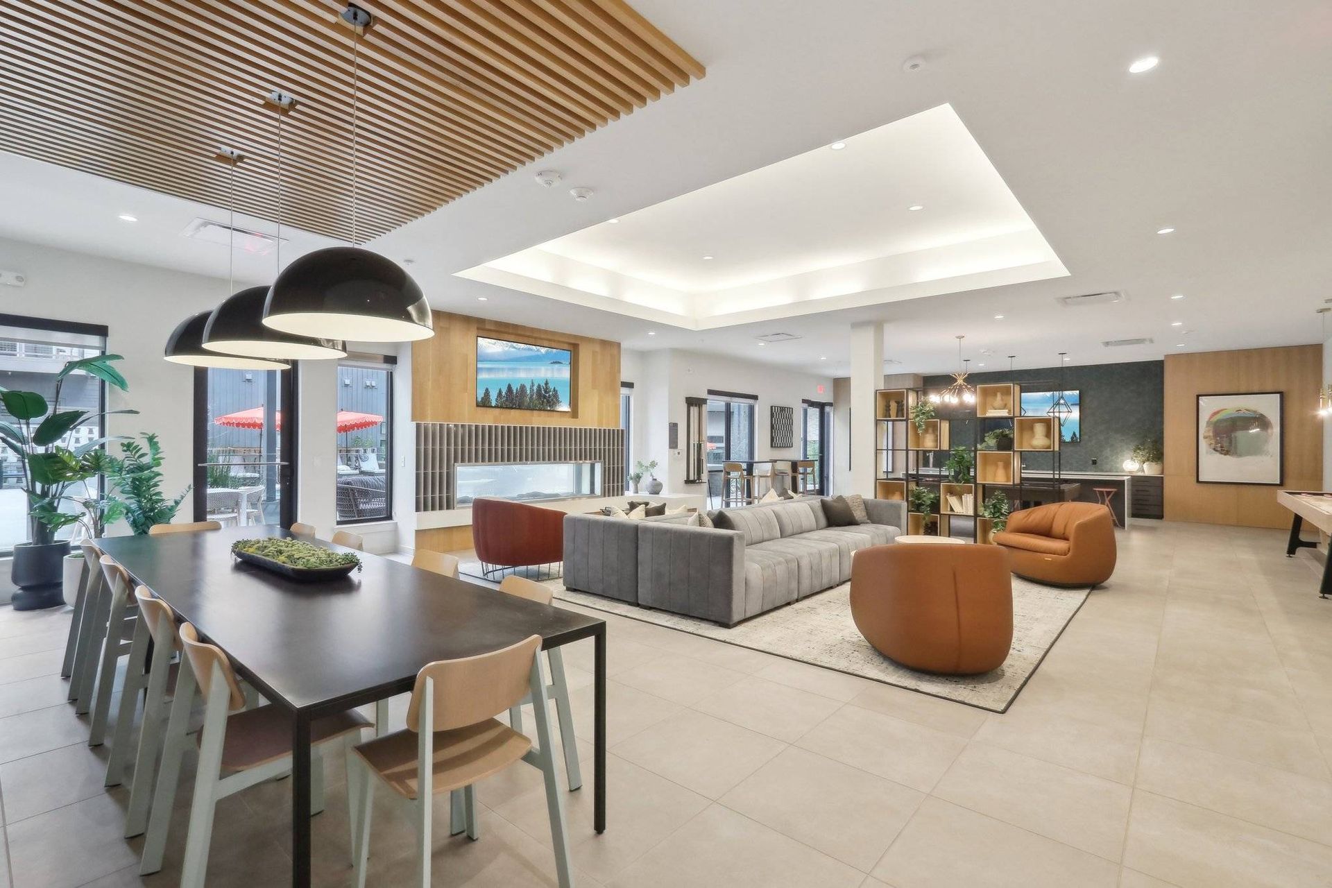 Bright community lounge with a large sofa, chairs, and a dining table in a modern amenity space.