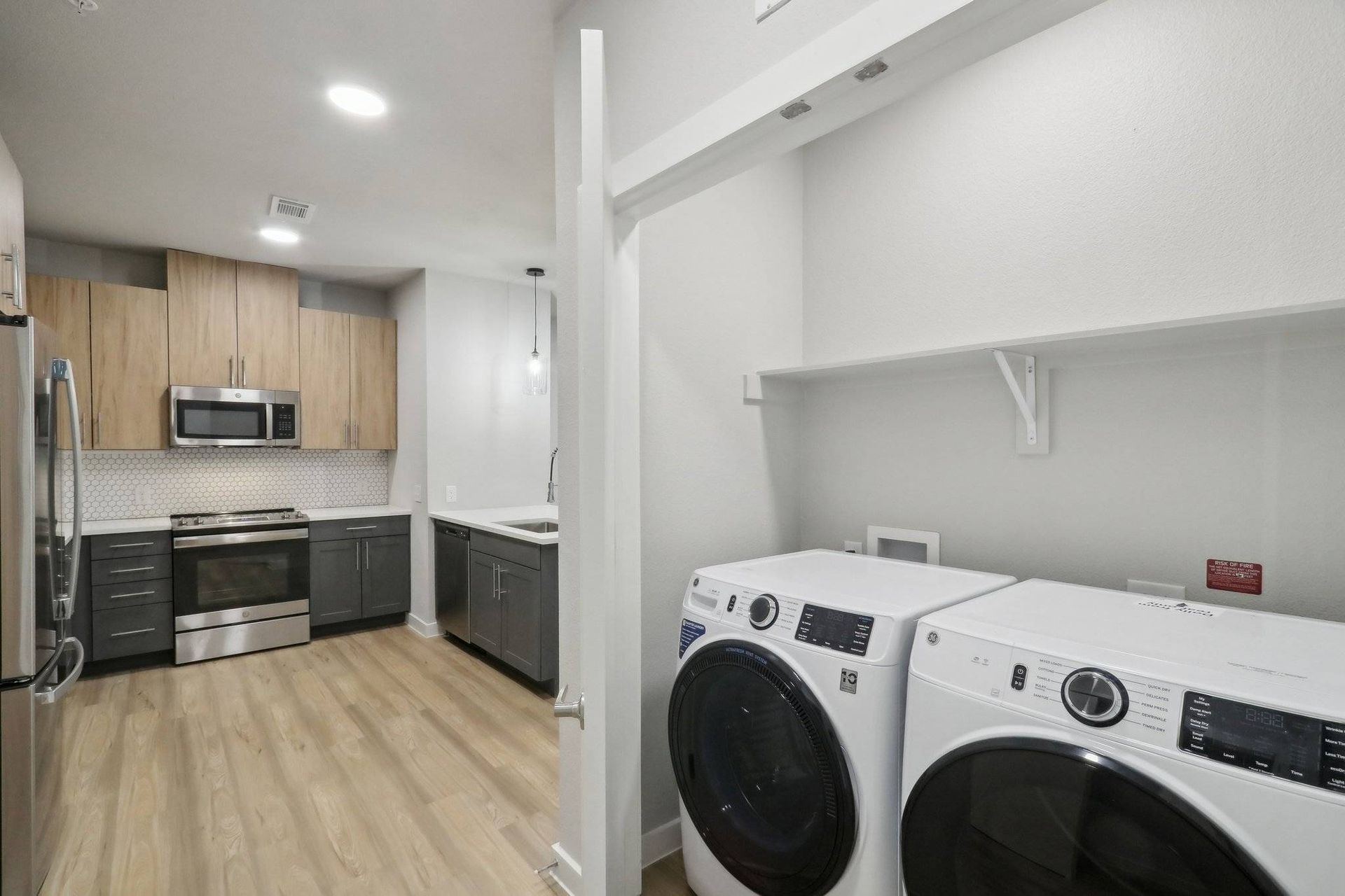 Modern kitchen with wood upper cabinets and stainless steel appliances; adjacent laundry area with washer and dryer.