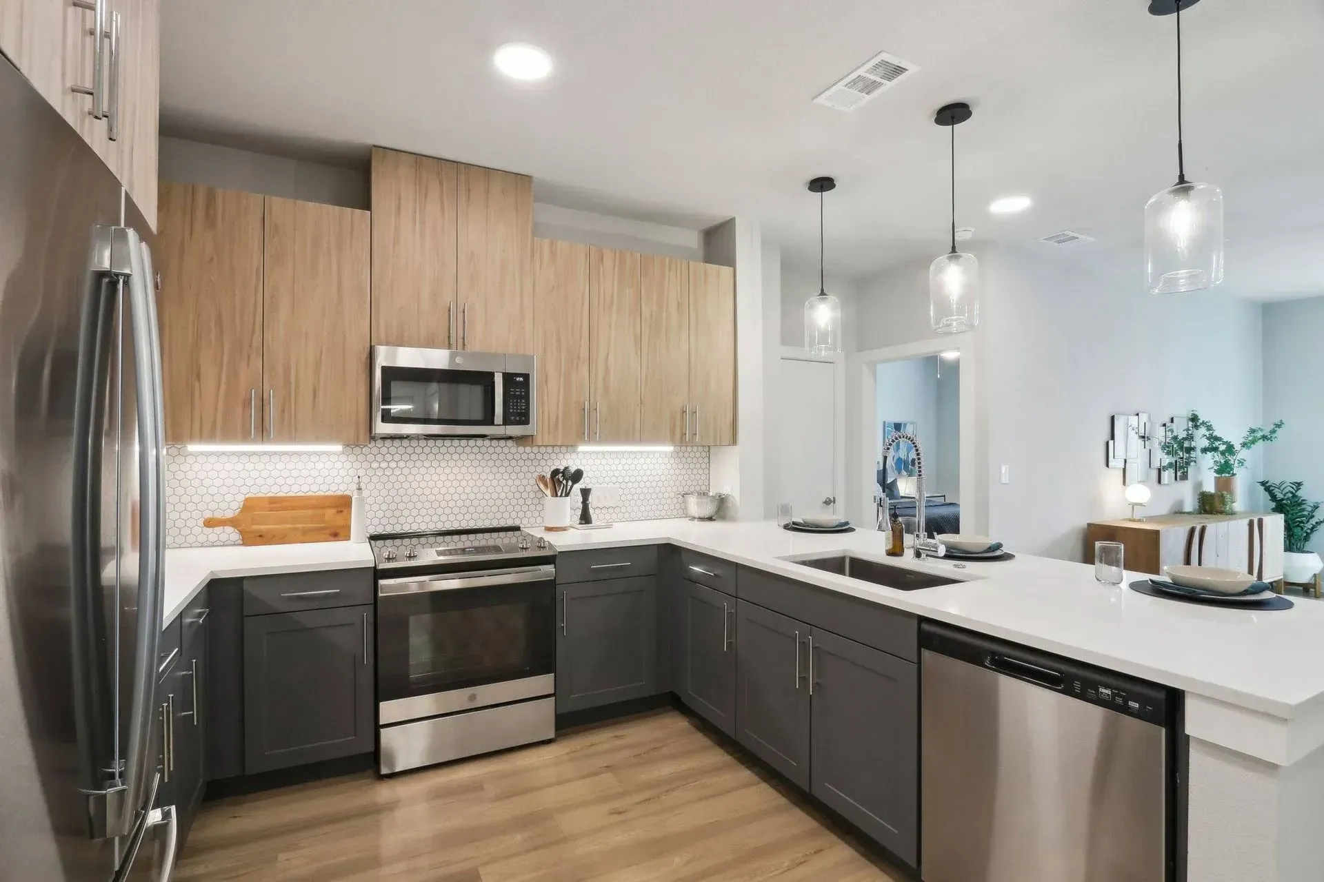 Modern kitchen with wood and gray cabinets, stainless steel appliances, and white countertops.