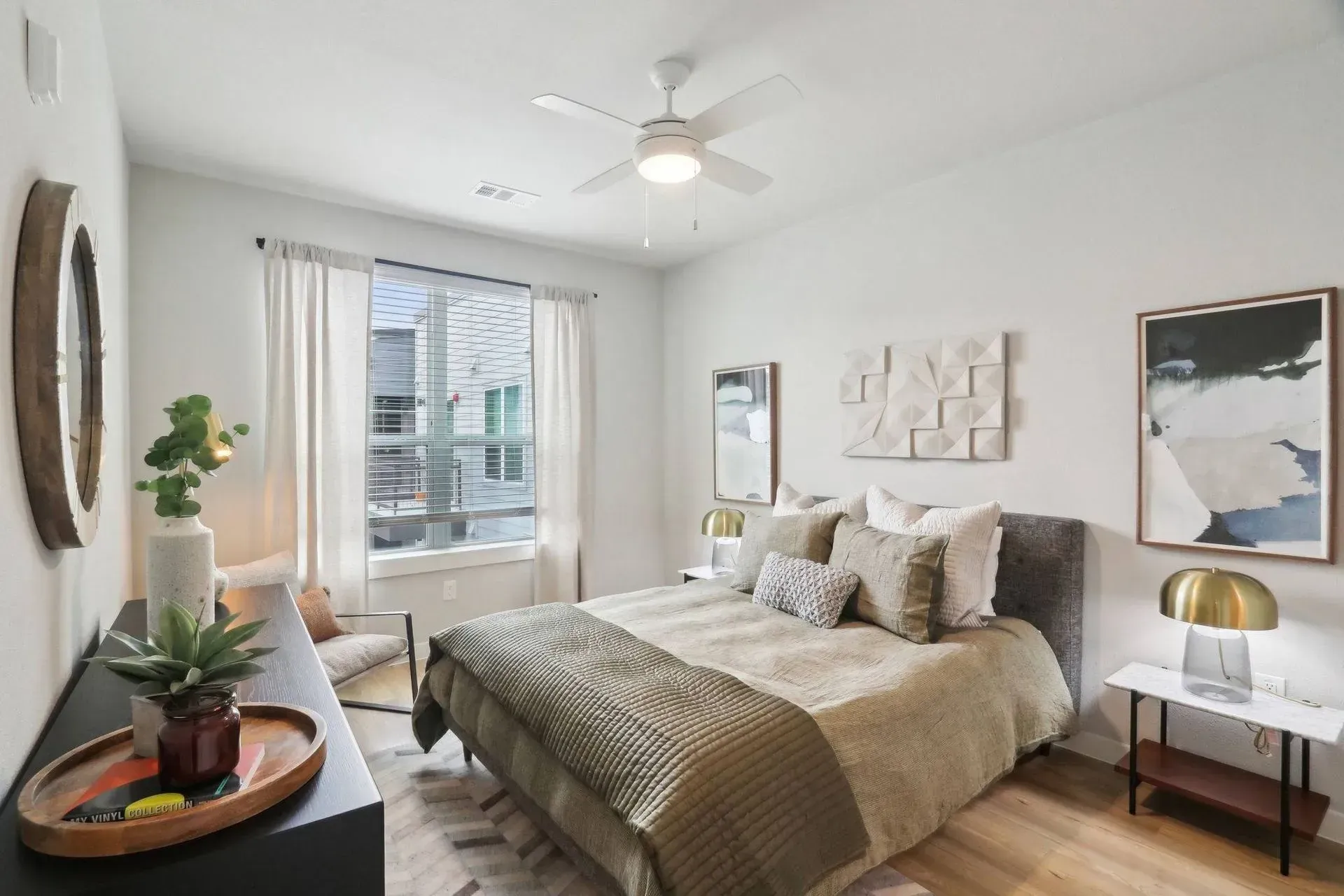 Bedroom with a bed, nightstand, dresser, artwork, and a window. Beige and white color scheme.