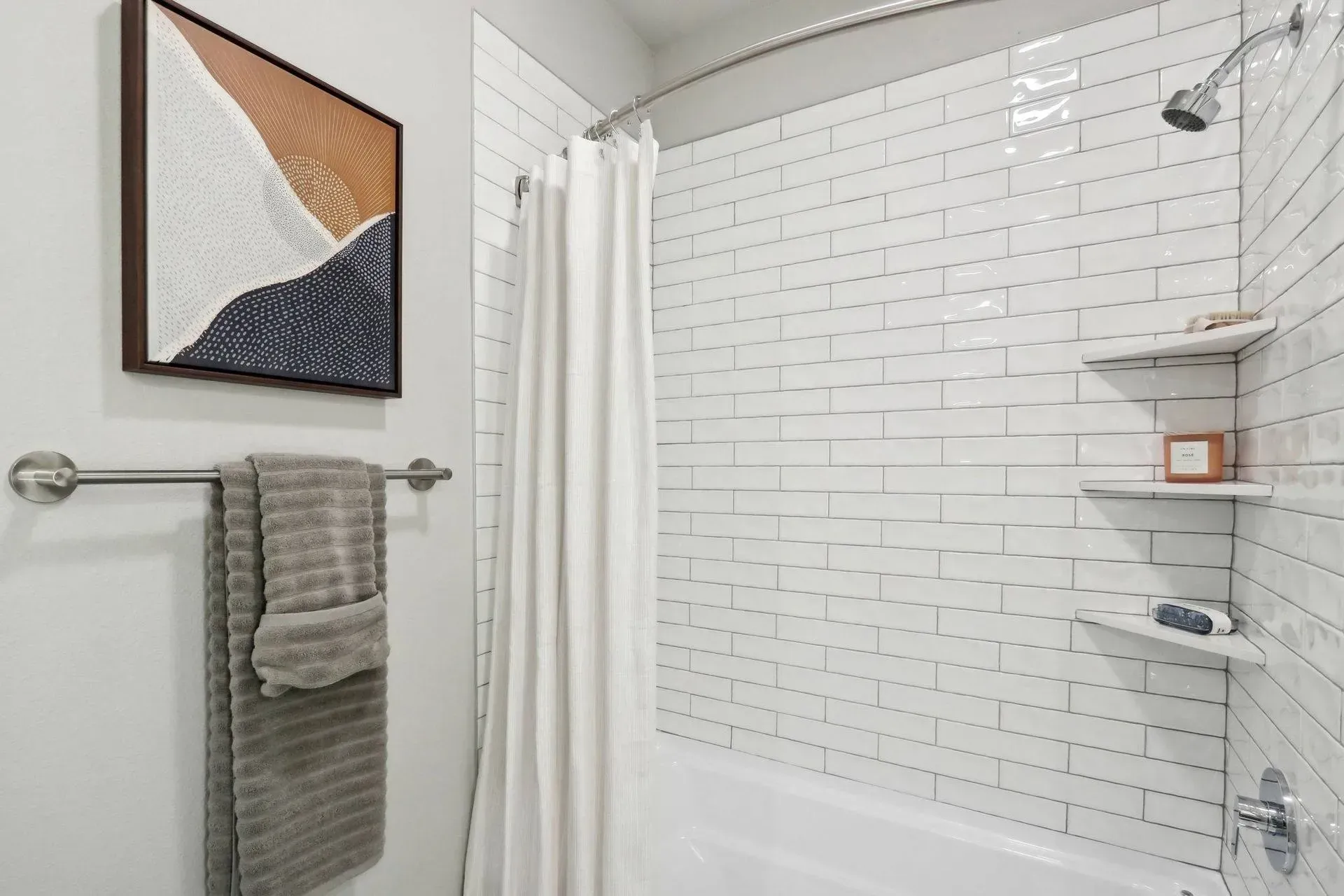 Bathroom with white subway tile, shower curtain, towels, and artwork.
