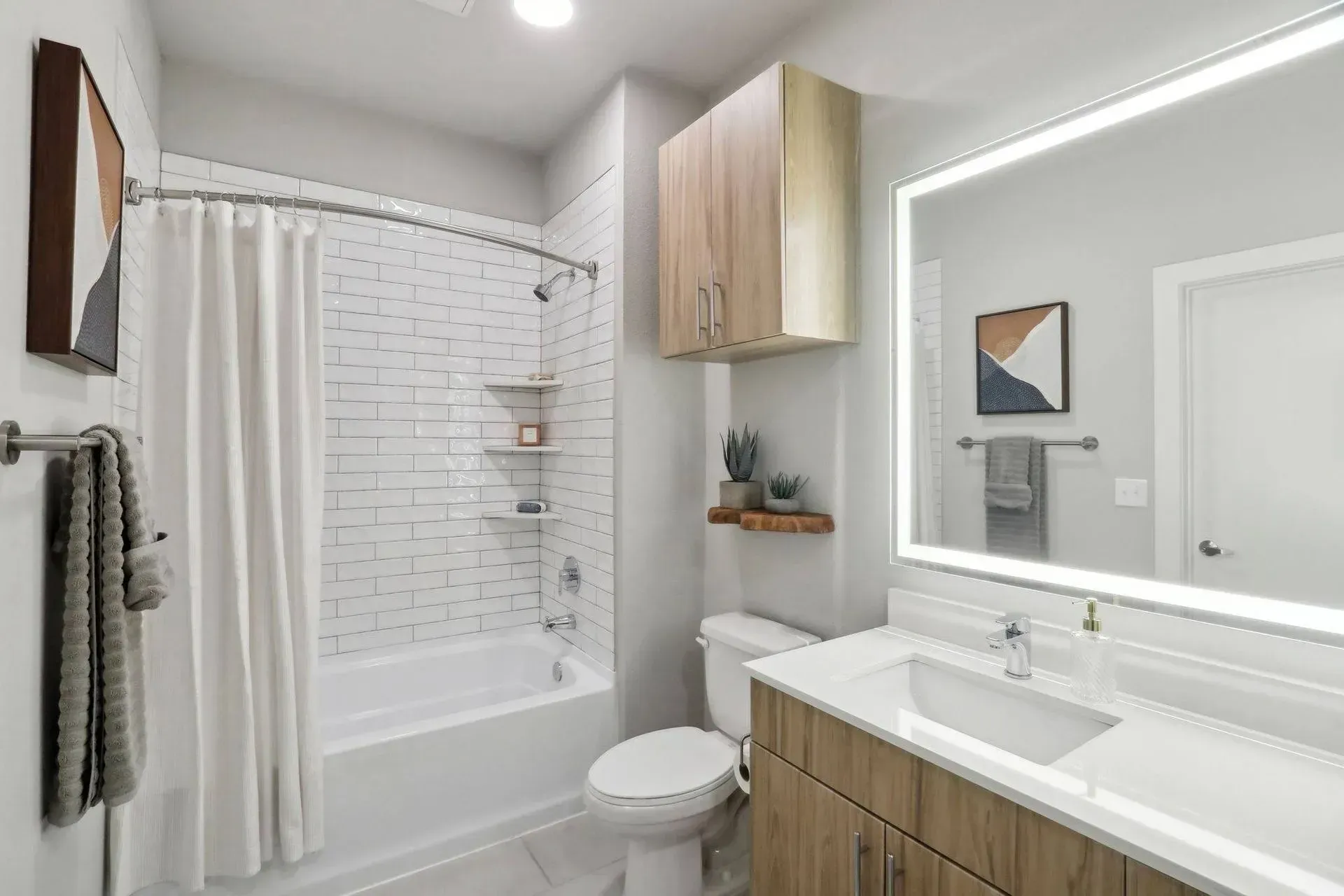 Modern bathroom with white subway tile, a bathtub, and wood-tone vanity and cabinets.