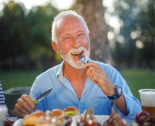 Elderly man eating on a bench outside