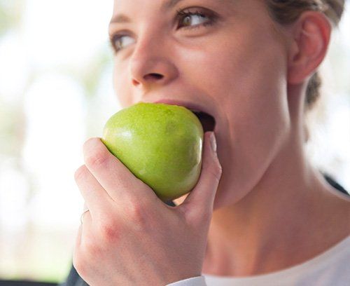 Close up of young woman biting a green apple